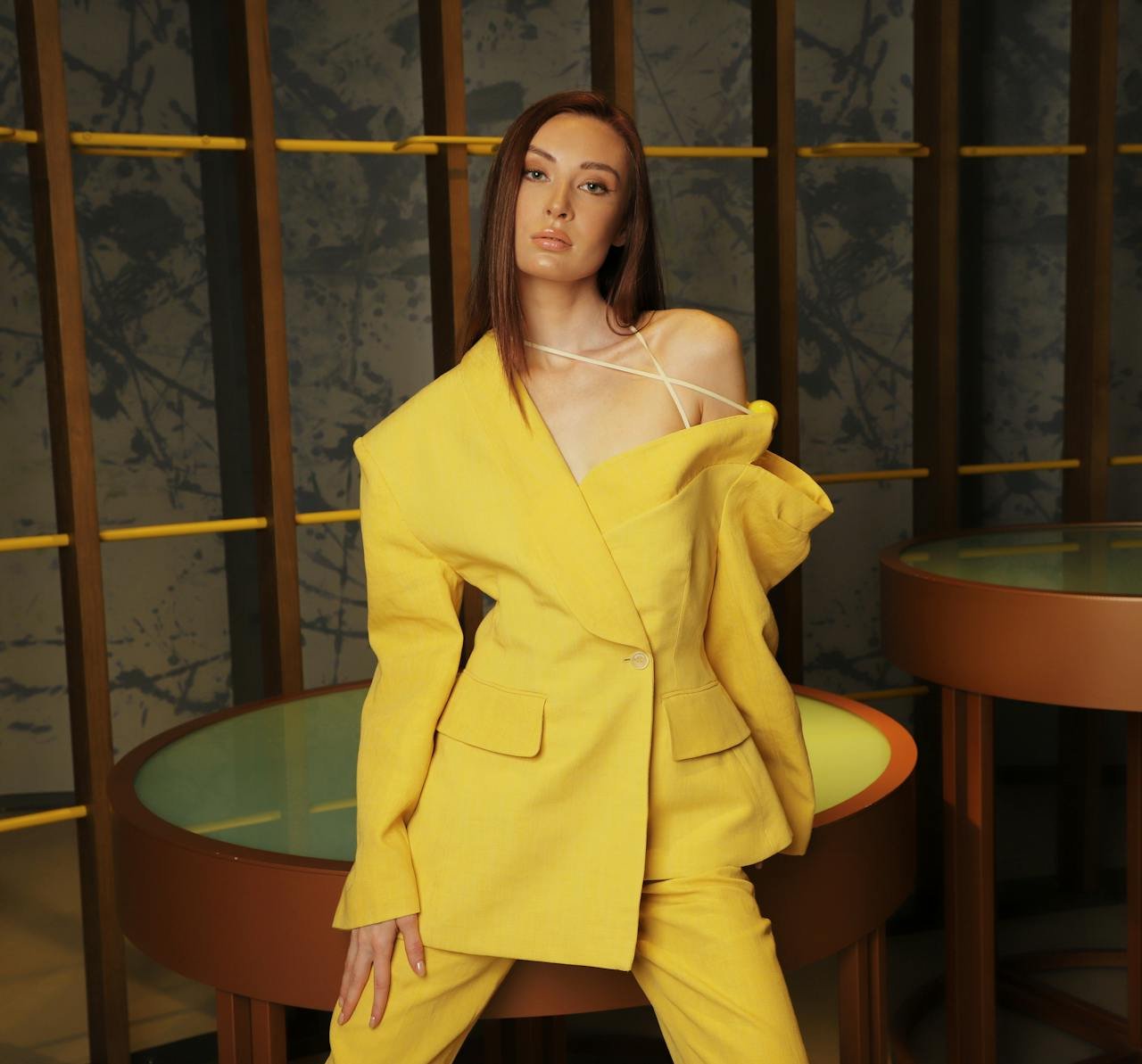 Home Fashionable woman posing in a yellow suit indoors, showcasing modern elegance.